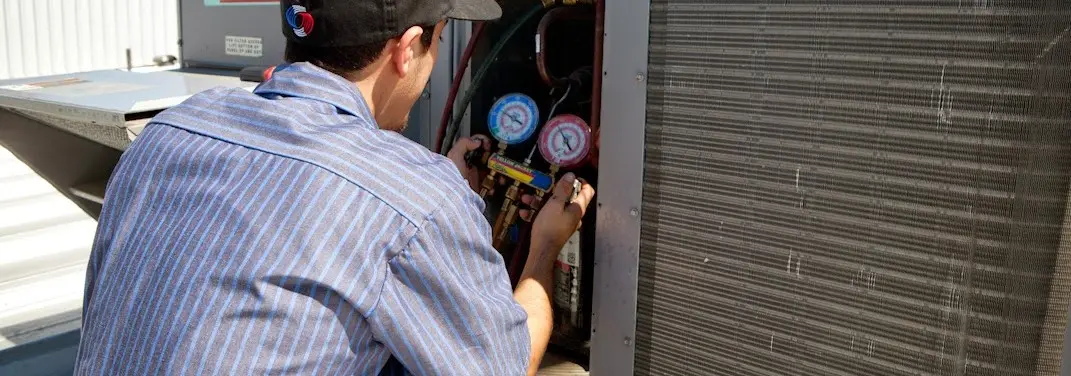HVAC technician servicing a condenser unit in Waterbury